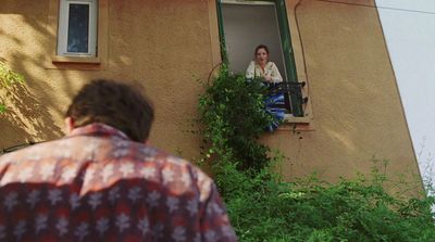 a man looking out of a window at a woman