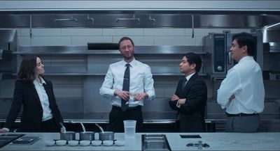 a group of people standing in a kitchen talking