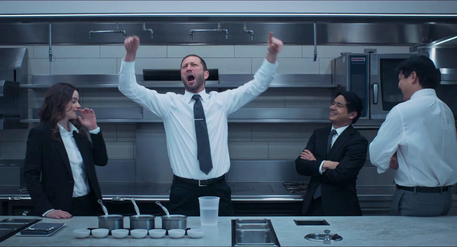 a group of people standing around a kitchen