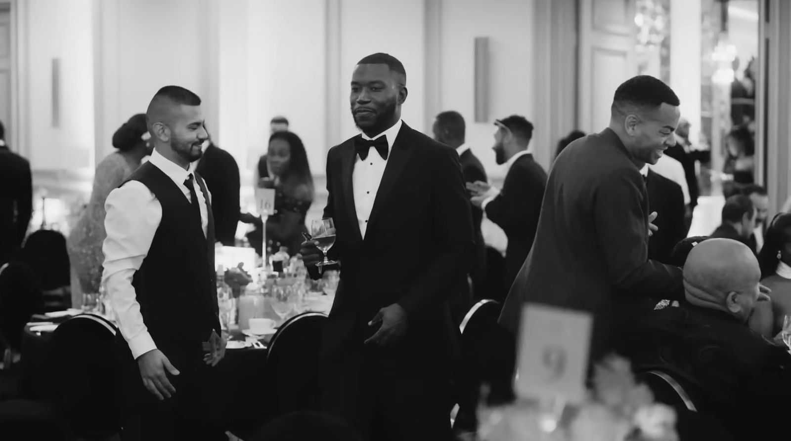 a group of men in tuxedos standing around a table