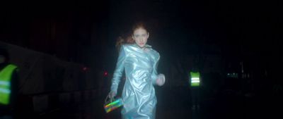 a woman in a shiny silver outfit walking in the dark