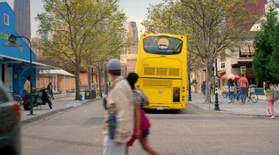 a yellow bus driving down a street next to tall buildings