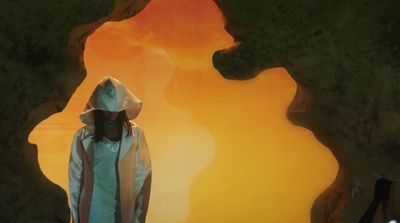 a man in a white raincoat is walking through a cave