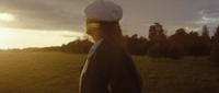 a man standing in a field with trees in the background