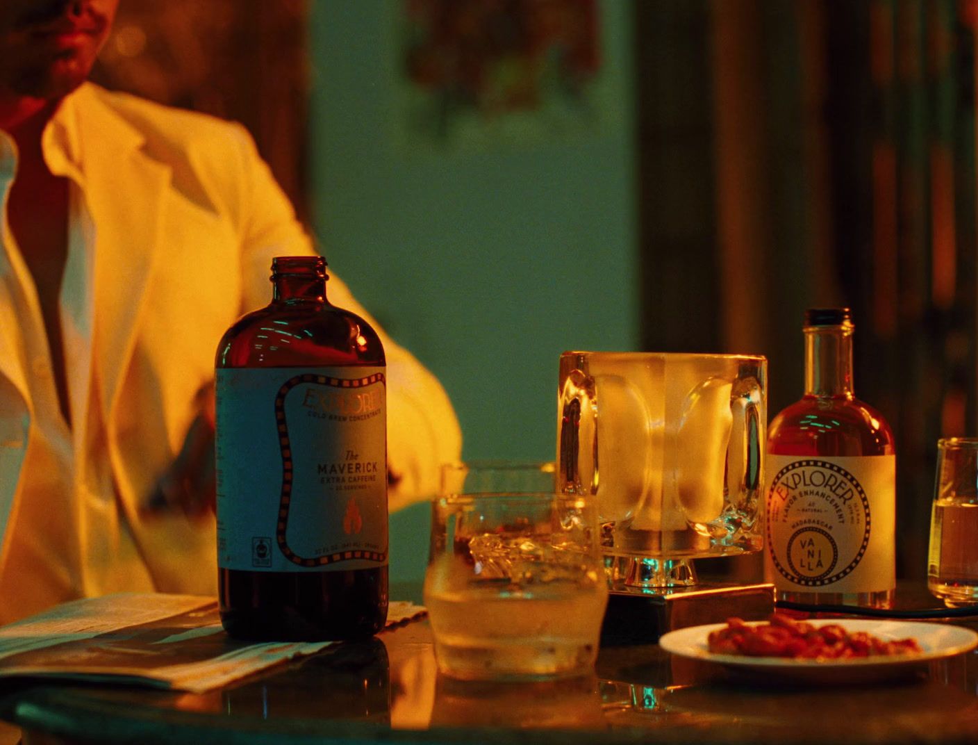 a man sitting at a table with a plate of food and a bottle of alcohol