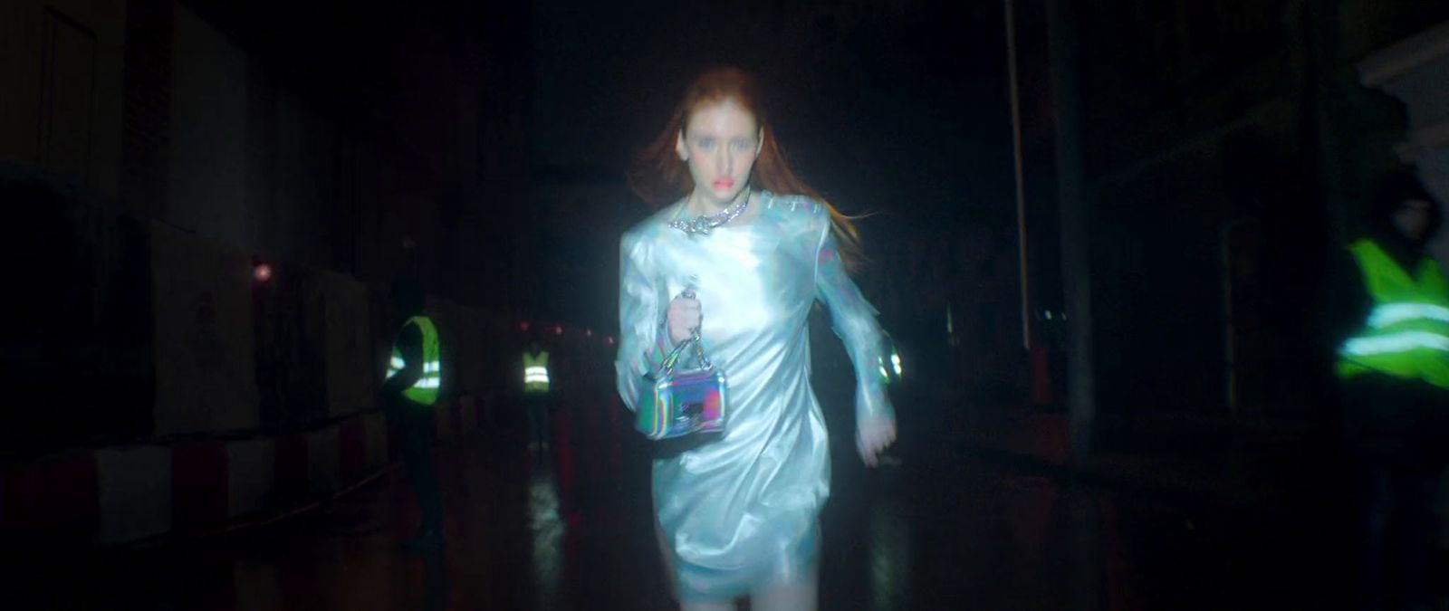 a woman in a white dress walking in the dark