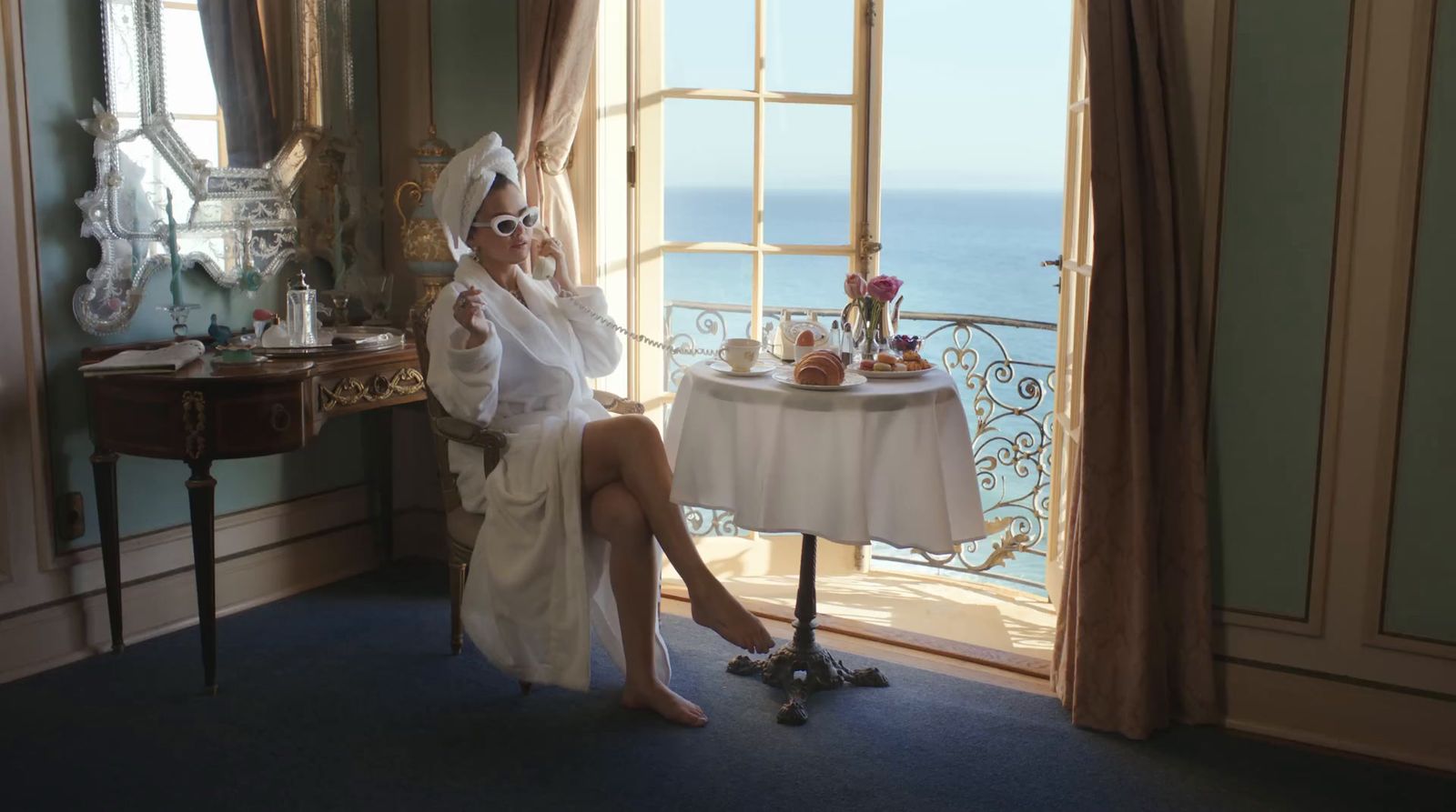 a woman in a bathrobe sitting at a table in front of a window