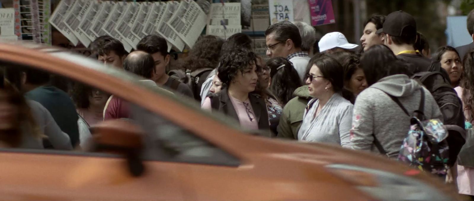 a crowd of people walking down a street next to a car