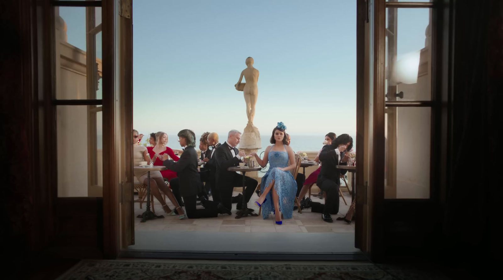 a group of people sitting at a table in front of a statue