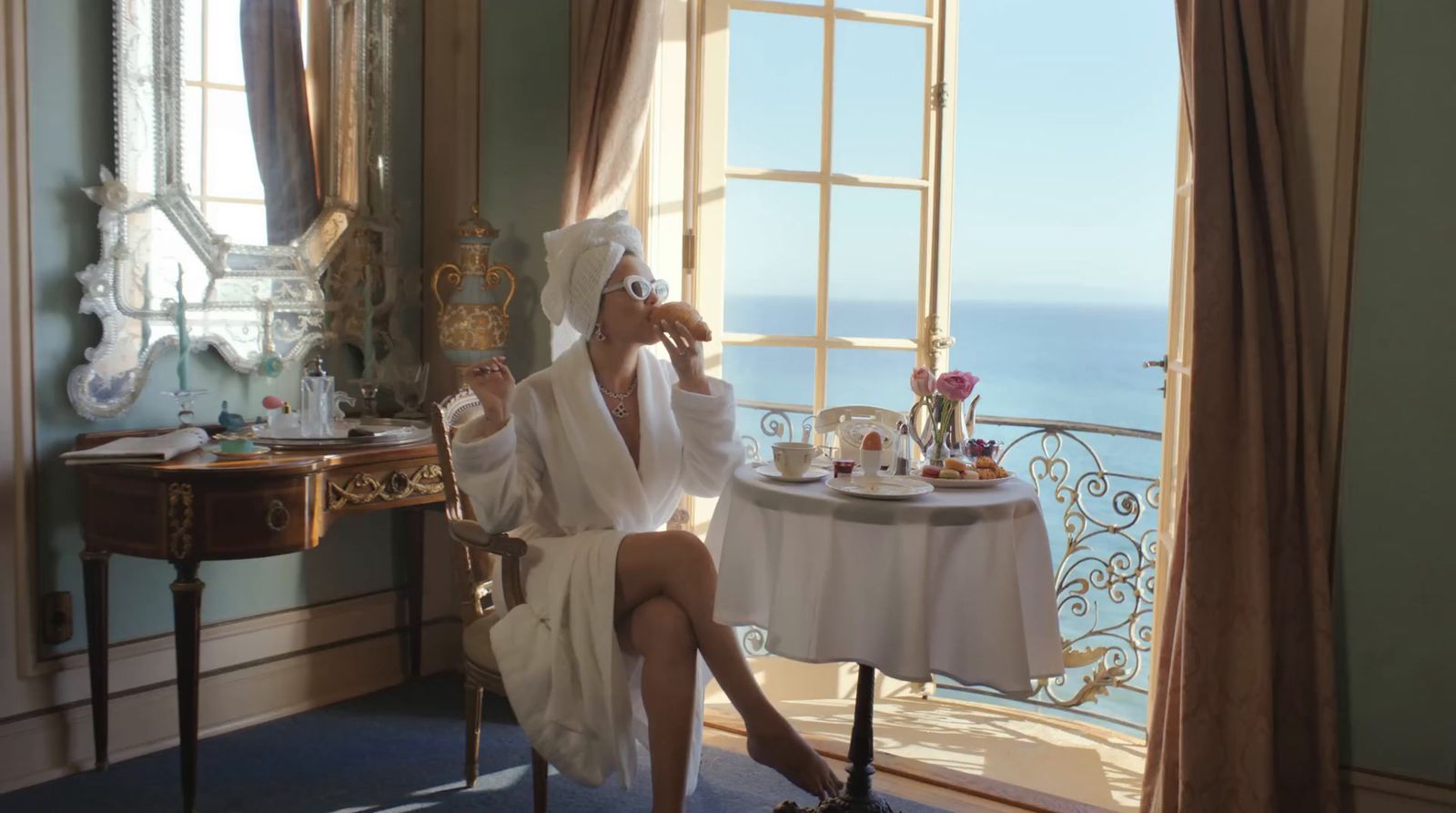 a woman in a bathrobe sitting at a table with a cake