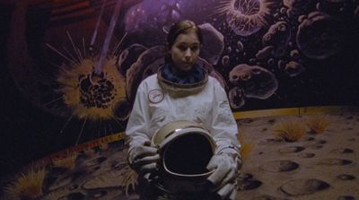 a woman in a space suit holding a helmet