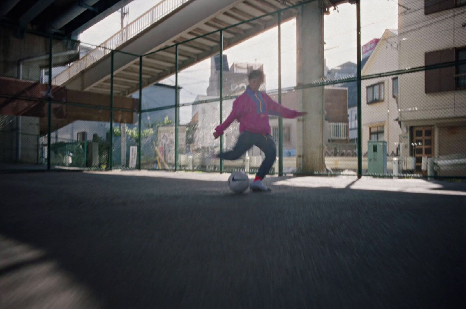 a young girl kicking a soccer ball under a bridge