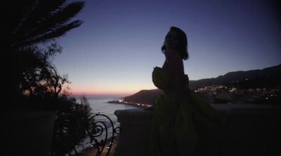 a woman in a yellow dress standing on a balcony