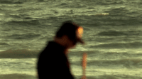 a man standing on top of a beach next to the ocean