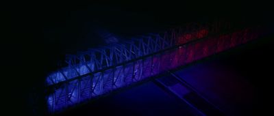 a red, white and blue light is shining on a bridge