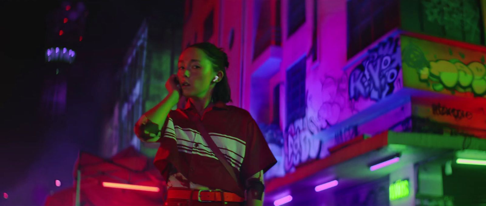 a woman talking on a cell phone in front of a neon building