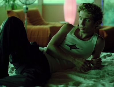 a man laying on a bed in a white tank top