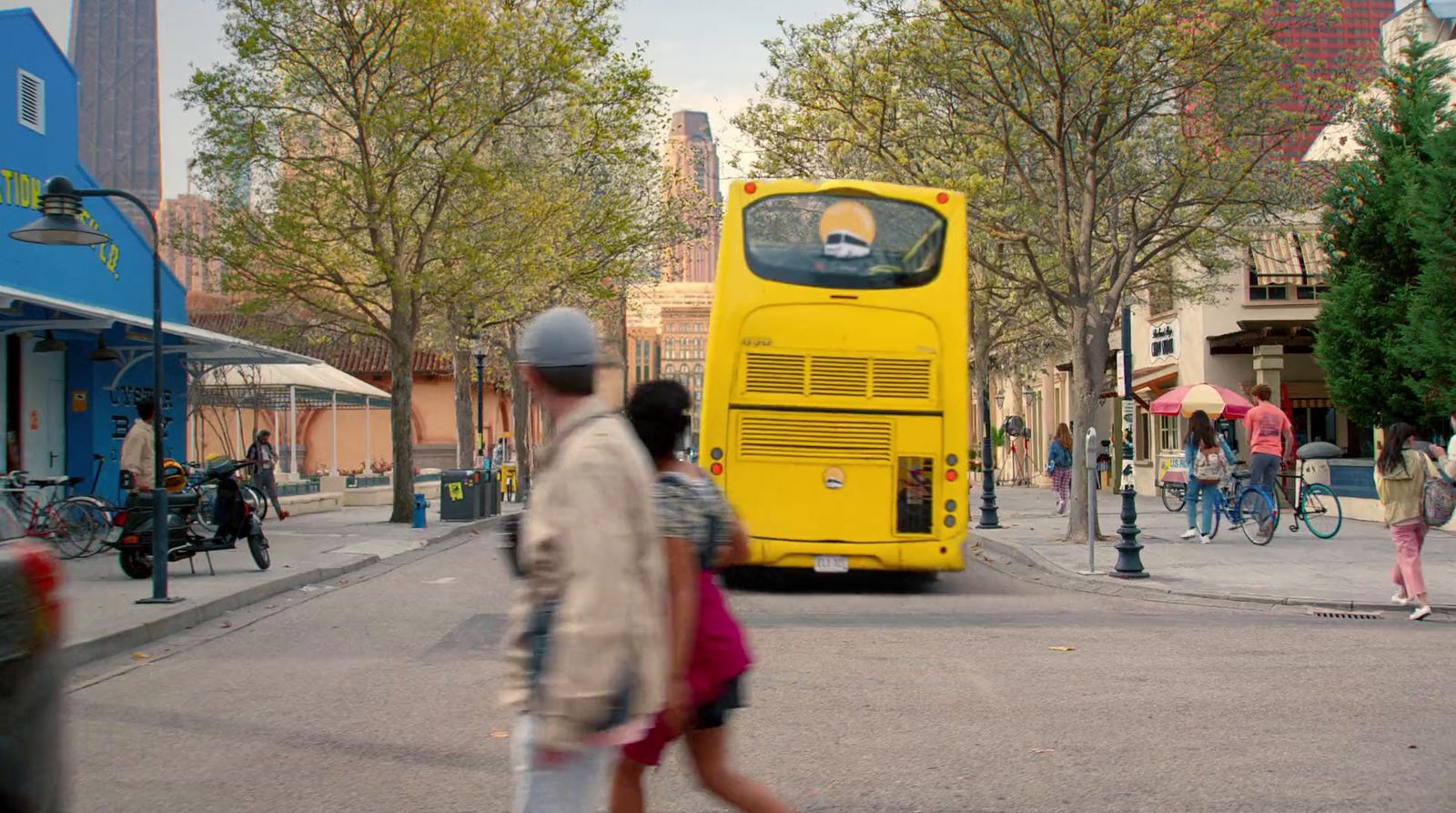 a yellow bus driving down a street next to tall buildings