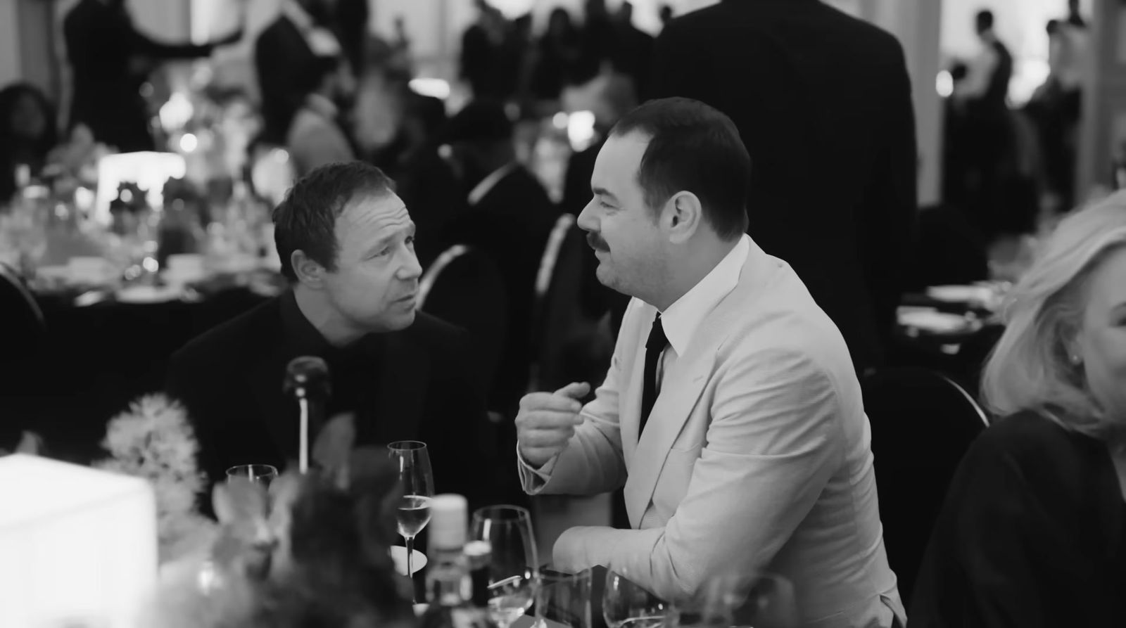 two men sitting at a table talking to each other