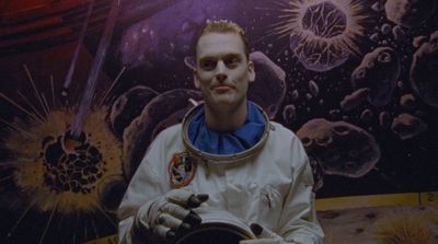 a man in a space suit standing in front of a painting