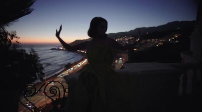 a woman in a dress standing on a balcony