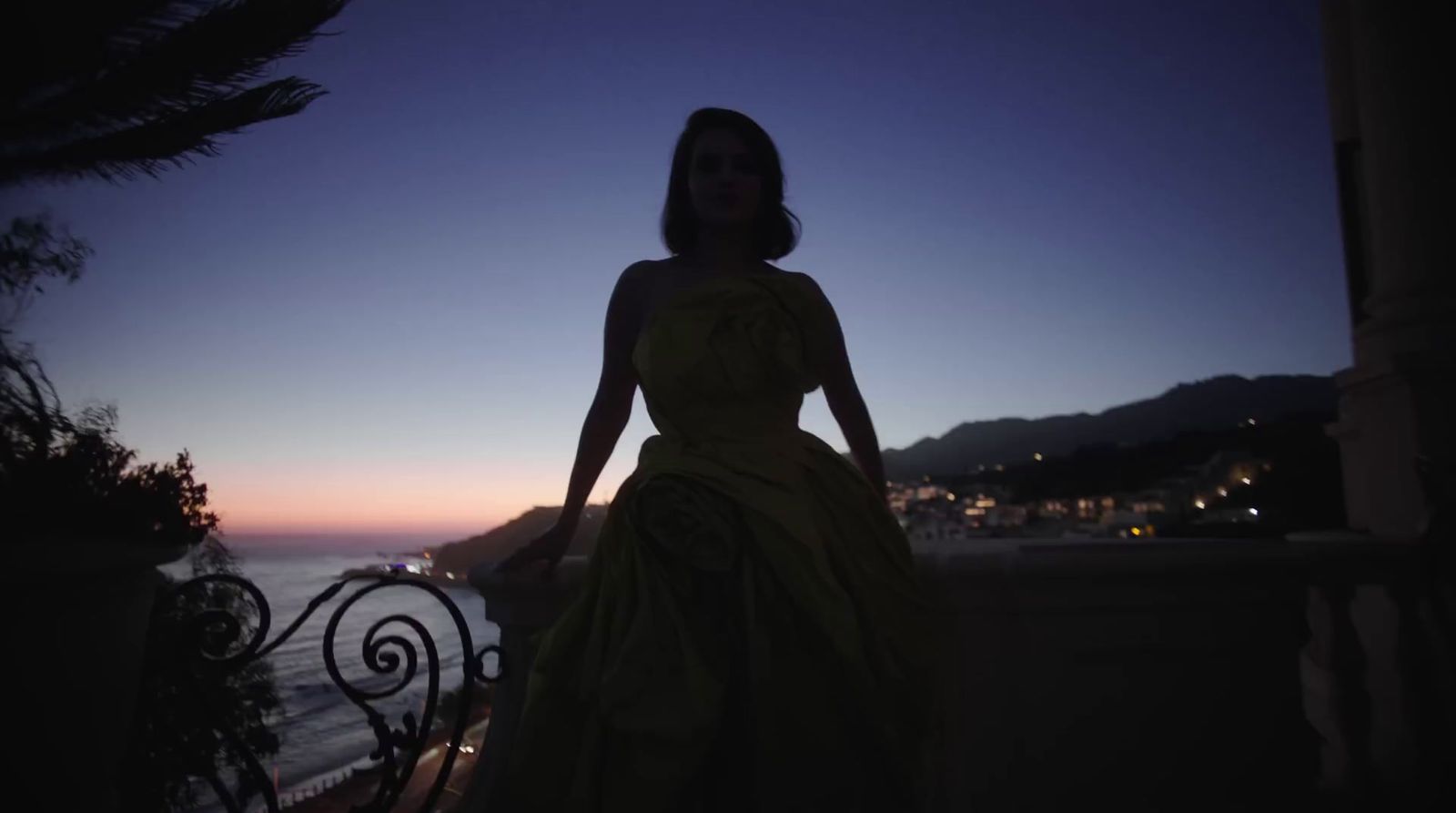 a woman in a dress standing on a balcony