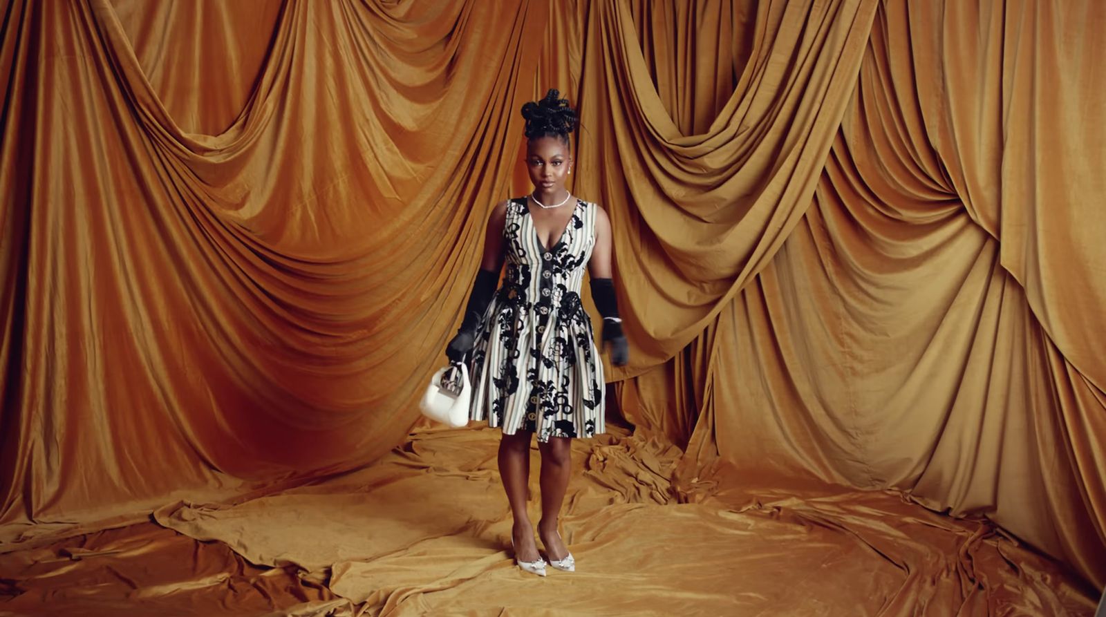 a woman standing in front of a gold curtain