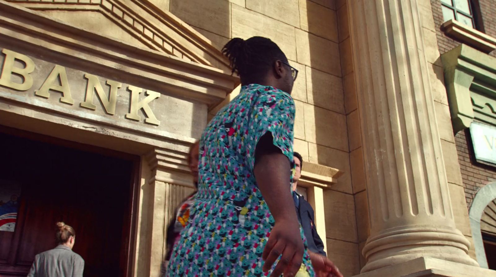 a woman in a blue dress is standing in front of a bank