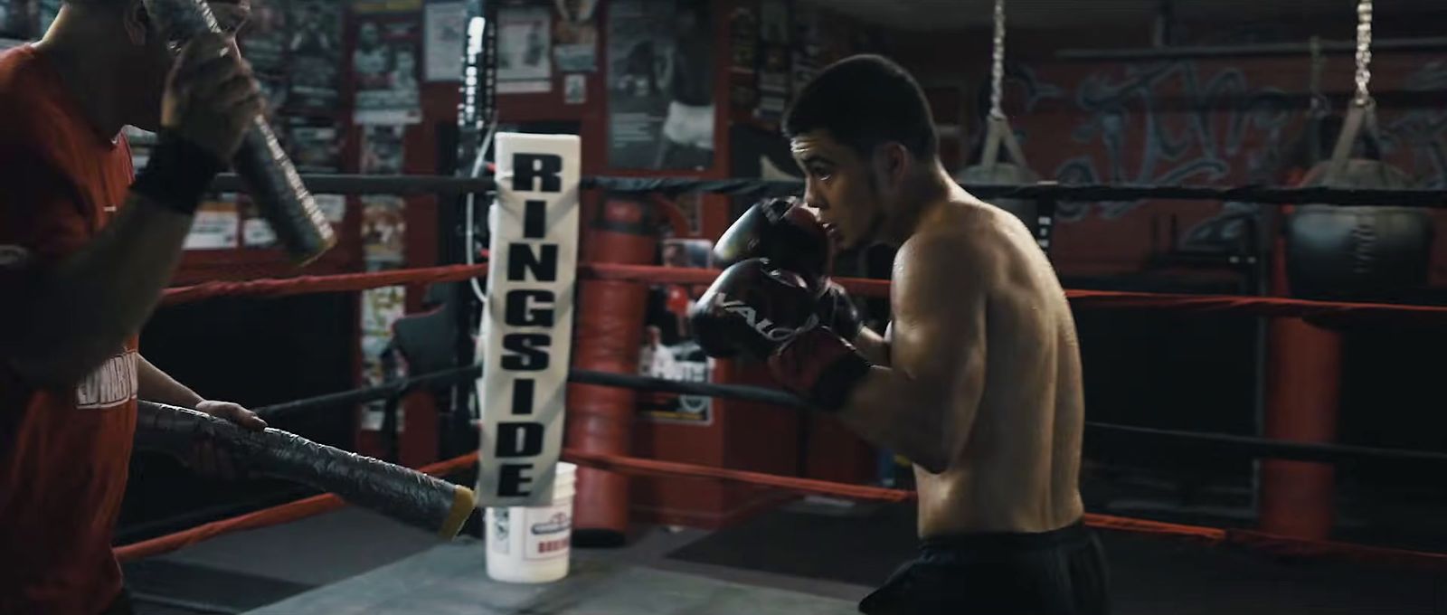 a man standing next to a punching bag in a boxing ring