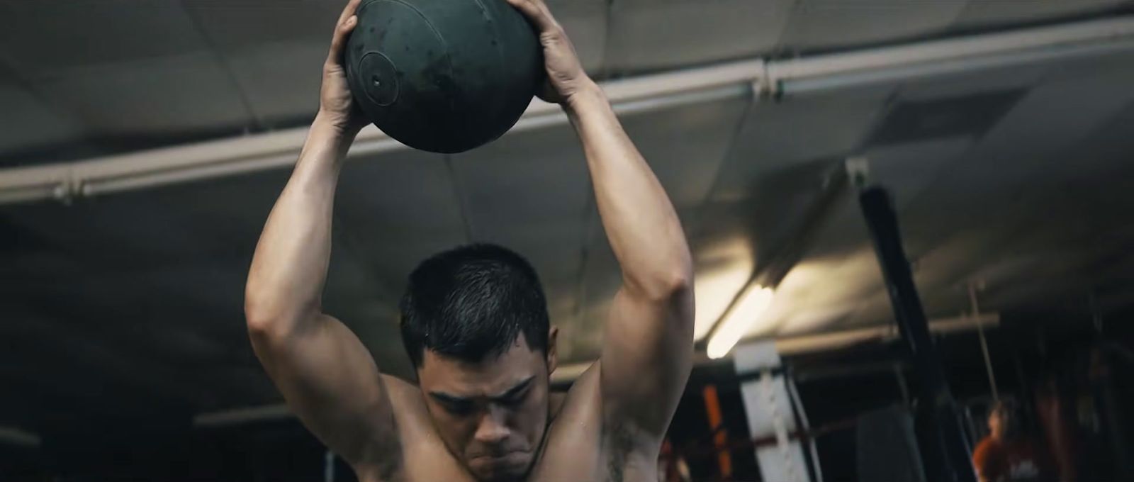 a man holding a medicine ball above his head