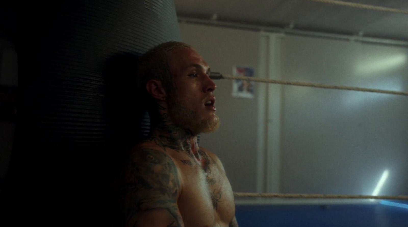 a man with tattoos standing in a ring