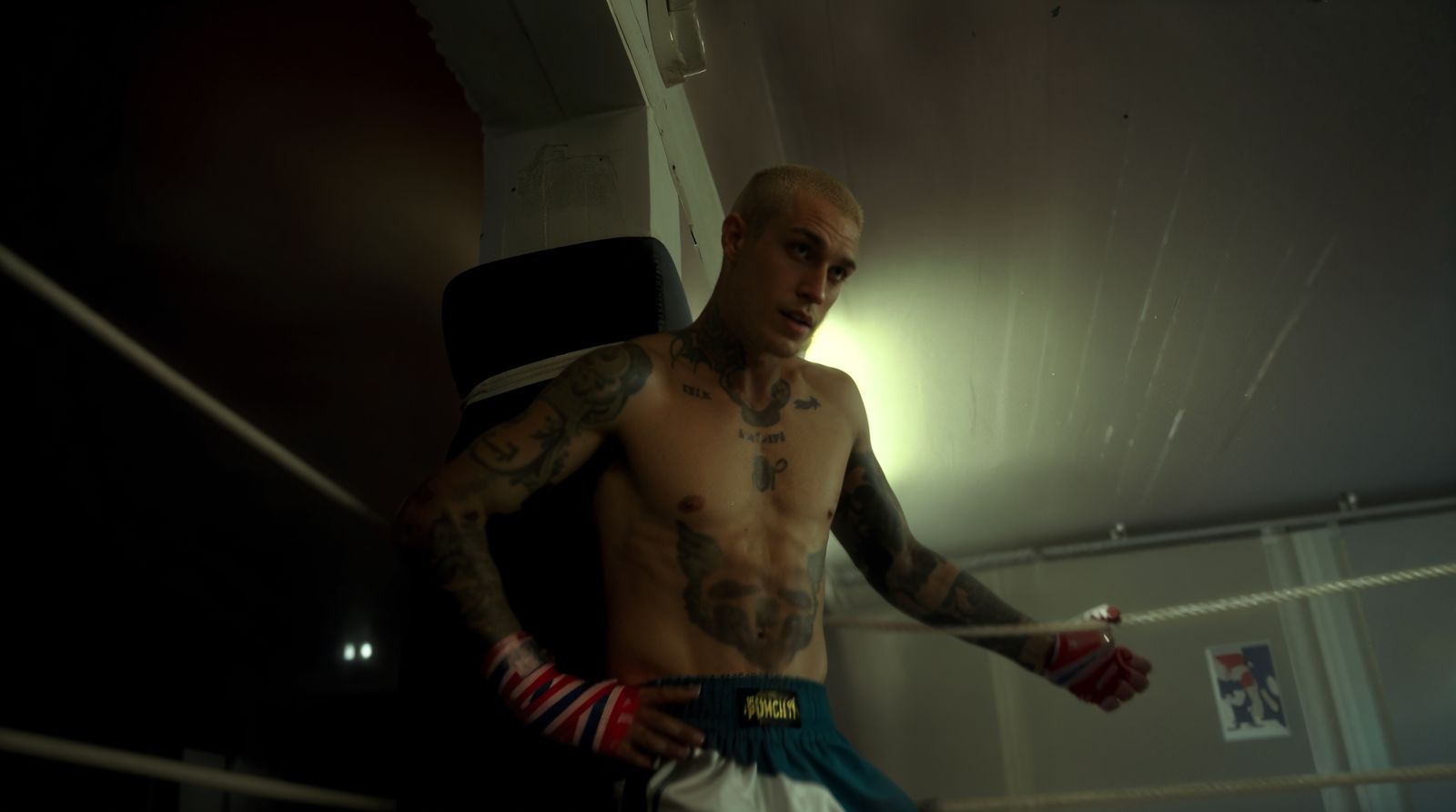 a man with a tattooed arm standing in a boxing ring