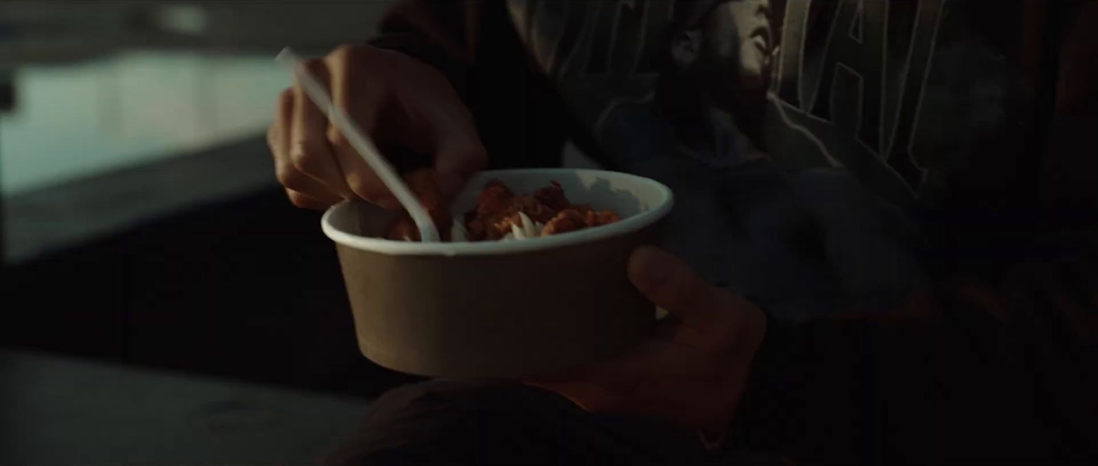 a person holding a bowl of food with chopsticks