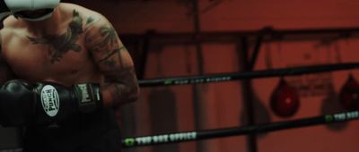 a tattooed man wearing boxing gloves in a boxing ring