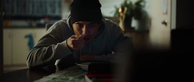 a man in a hoodie eating food at a table