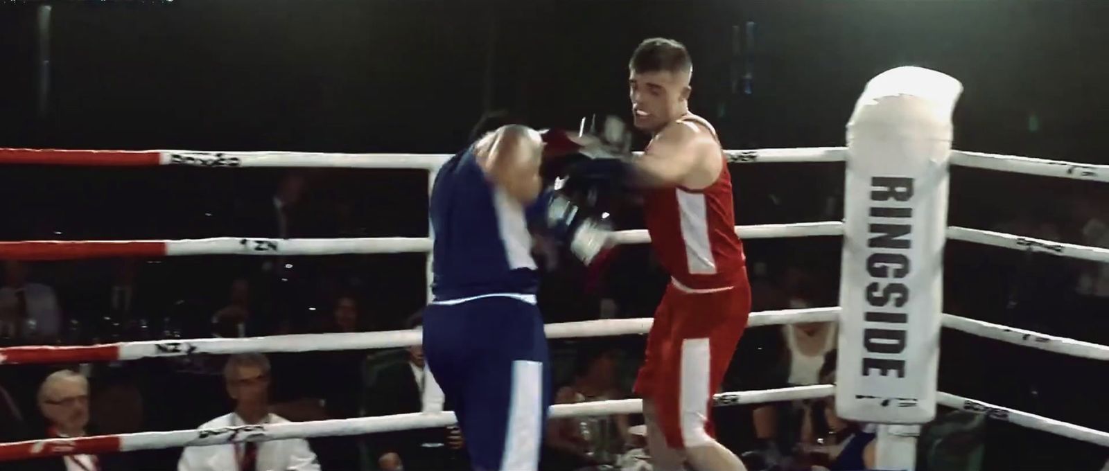 two men boxing in a ring with a crowd watching