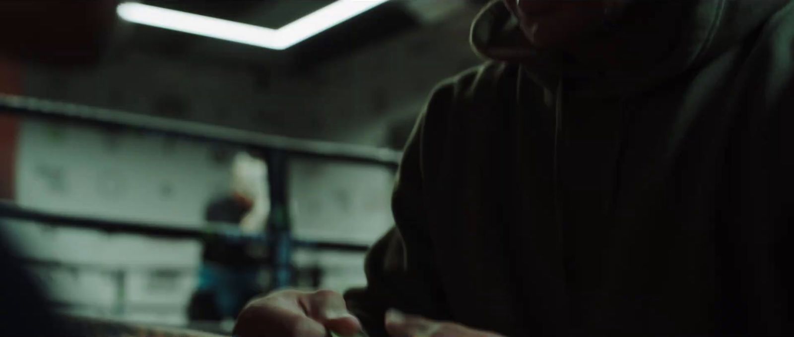 a man in a black hoodie cutting a piece of cake