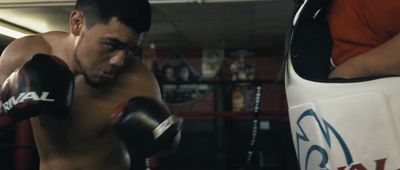 a shirtless man wearing boxing gloves in a boxing ring