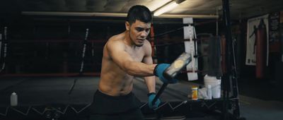 a shirtless man wearing boxing gloves in a boxing ring