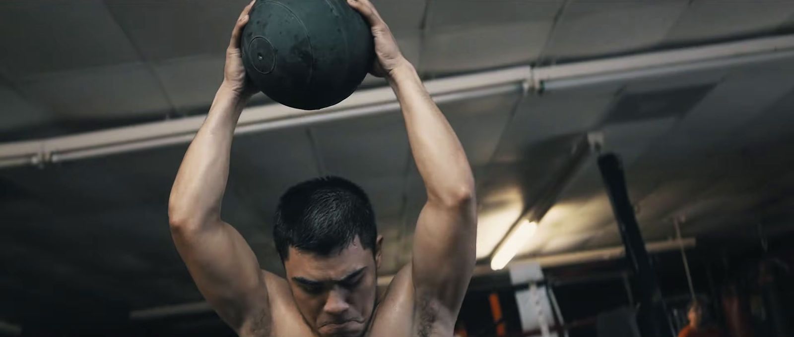 a man holding a medicine ball above his head