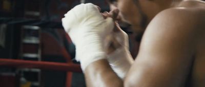 a shirtless man wearing boxing gloves in a boxing ring