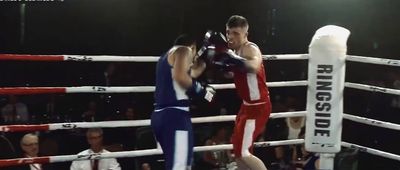 two men boxing in a ring with a crowd watching