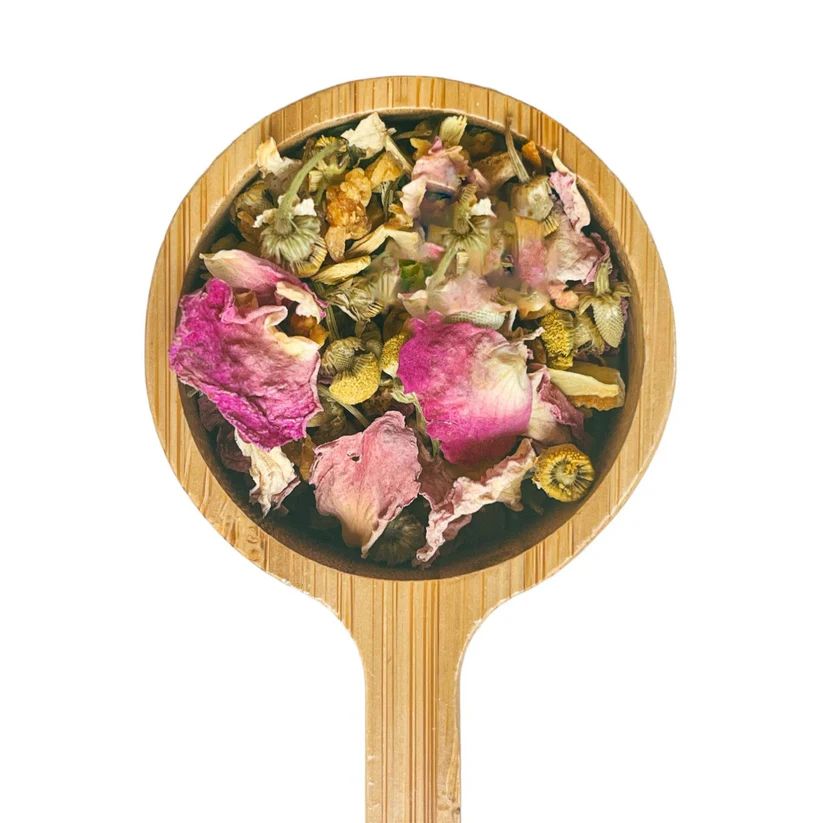 a wooden spoon filled with dried flowers on top of a white background