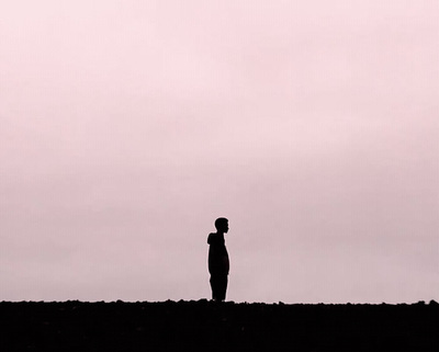 a person standing on a hill with a kite in the sky