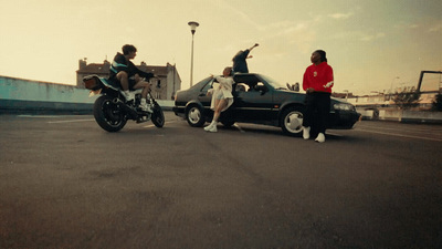 a group of people standing around a car and a motorcycle