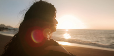 a woman standing on a beach next to the ocean