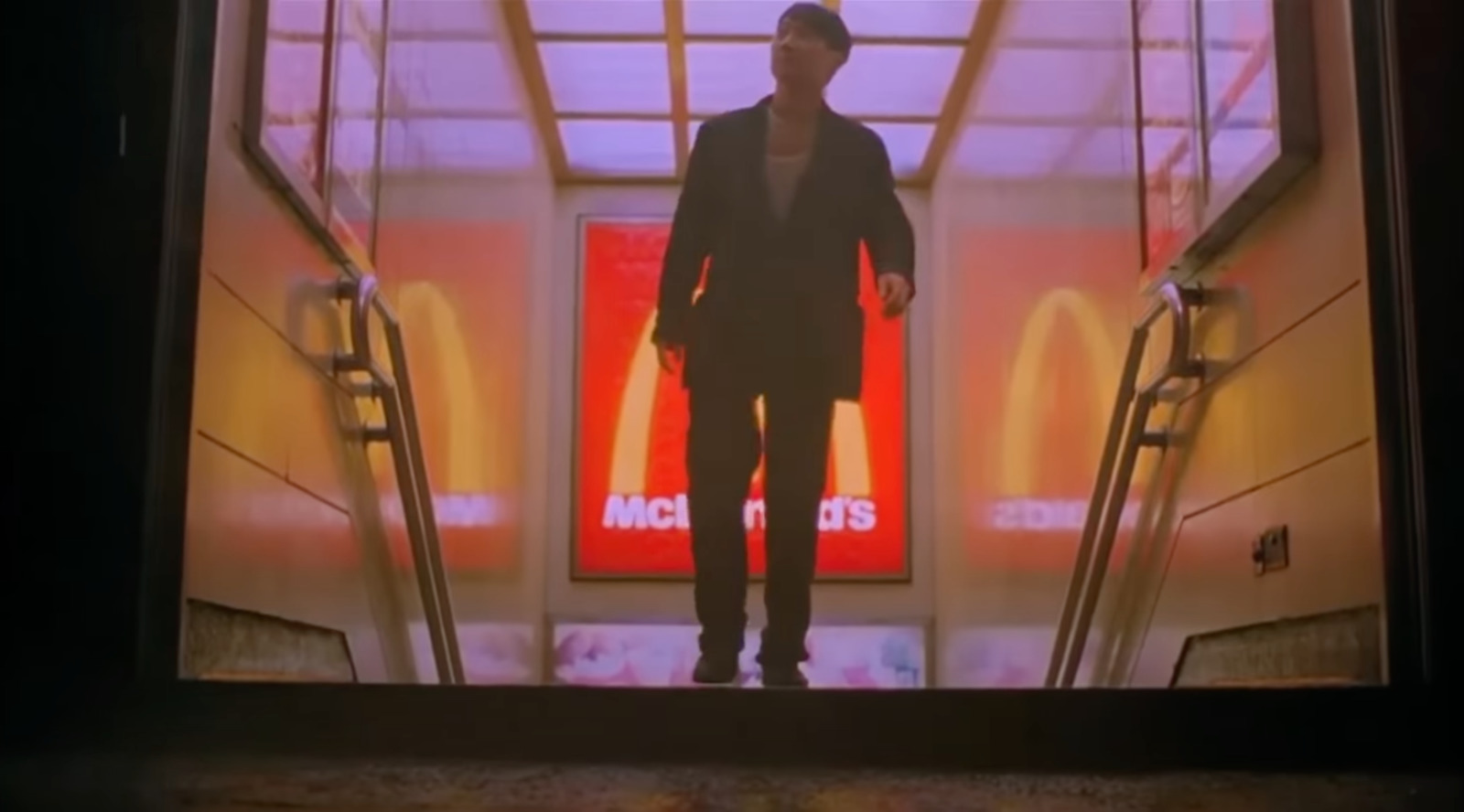 a man standing on an escalator in front of a mcdonald's sign