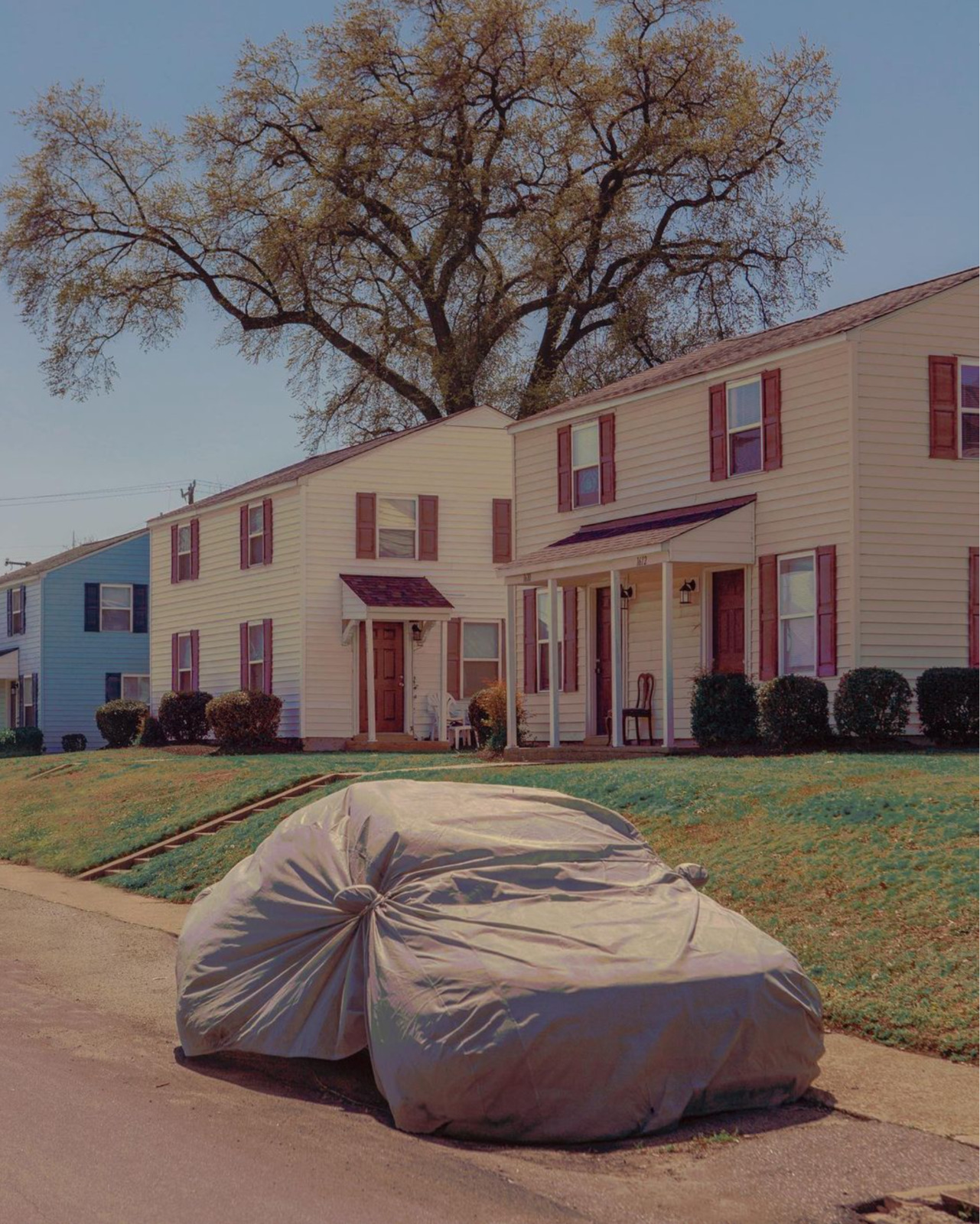 a car covered in a tarp parked in front of a house