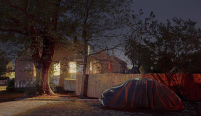 a car covered in a tarp parked next to a tree