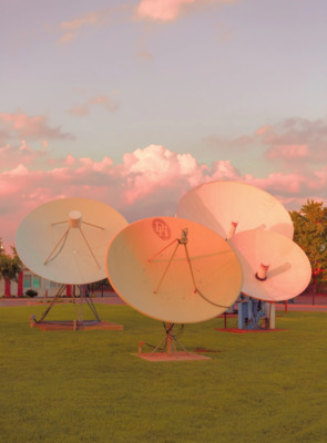 a group of satellite dishes sitting on top of a lush green field